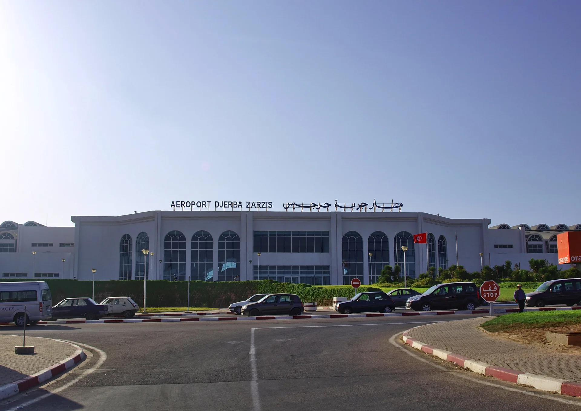 Façade de l'aérogare de l'aéroport de Djerba-Zarzis, avec l'enseigne du terminal et le parking visiteurs