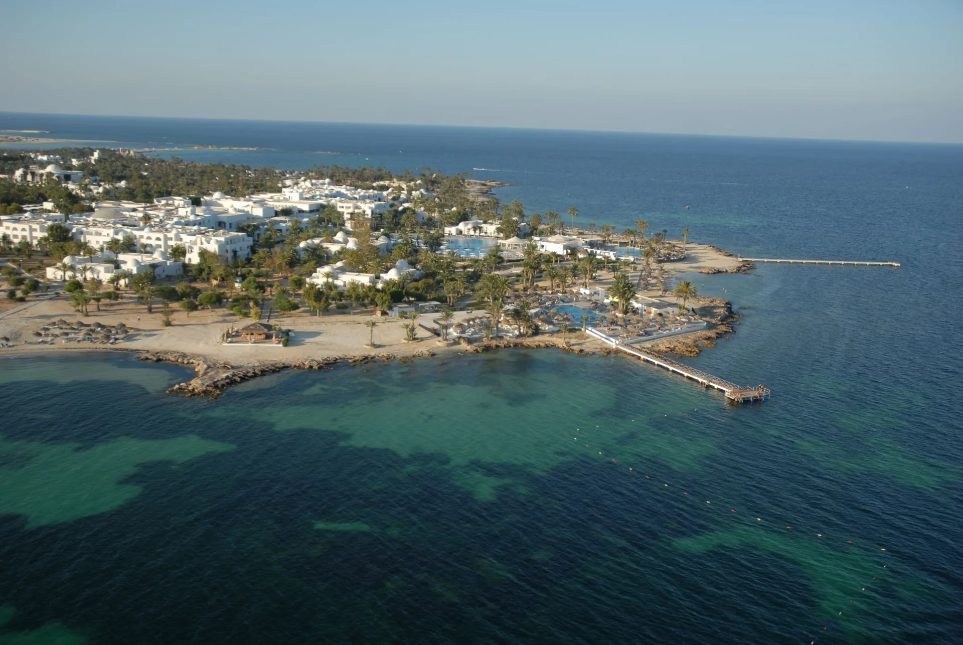 Vue aérienne du littoral de Djerba, plage et architecture traditionnelle blanche en bord de mer